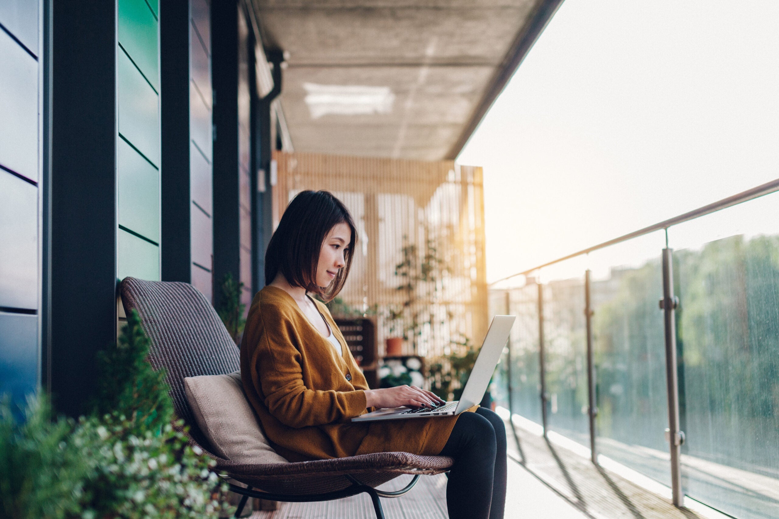 Woman looking at laptop while sitting on a balcony