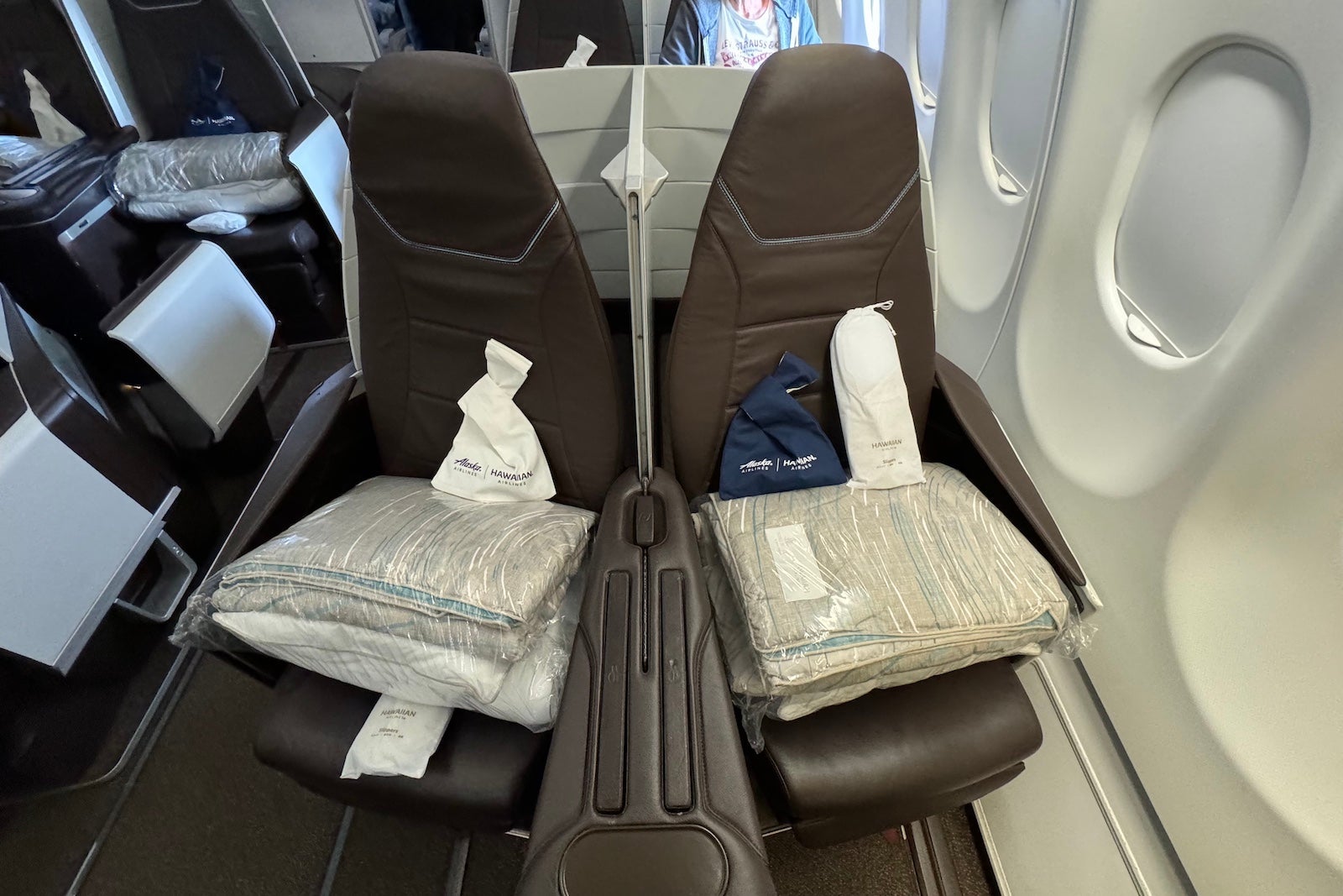two airplane seats with wrapped blankets and pillows