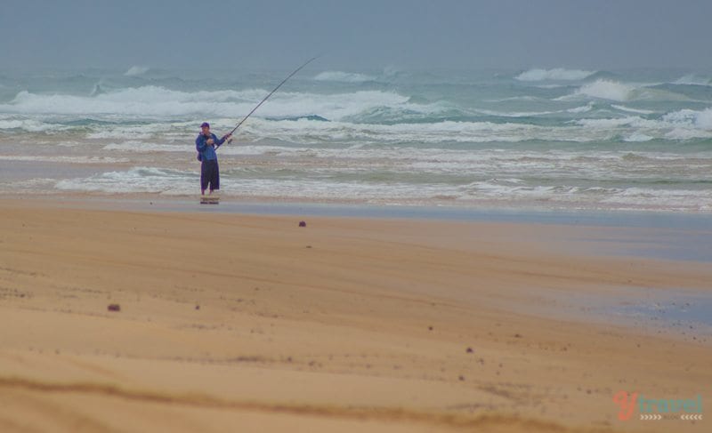 person fishing on the beach on k'gari