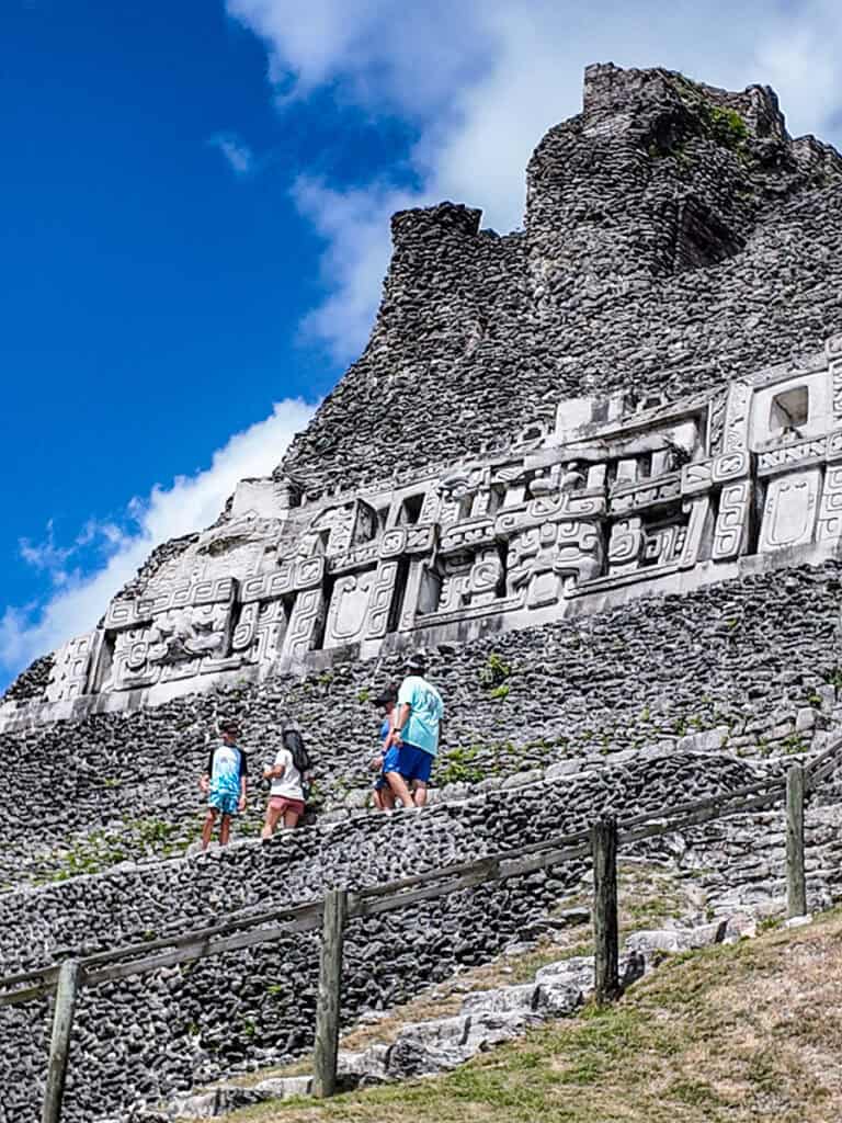 people walking past frieze etched into wall of el castillo