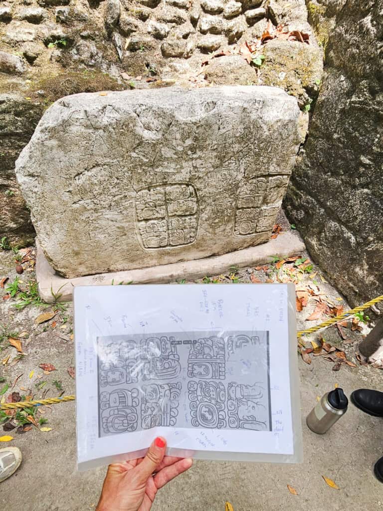 heiroglpyhs carved into rock nd lady holding up a paper version next to it