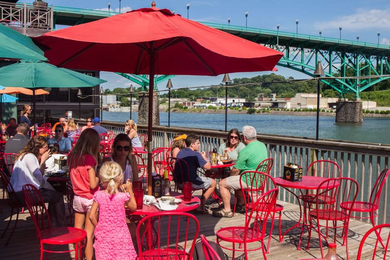 people sitting at red tables beside the river at Calhoun's