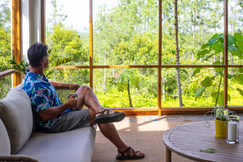man sitting in screened in porch with jungle views