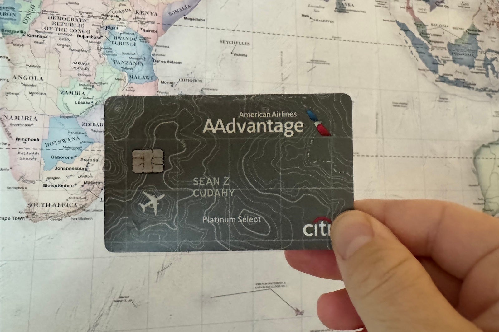 a hand holding a credit card in front of a map