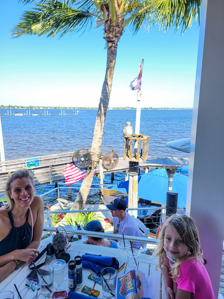 woman and girl sitting at restaurant table overlooking water
