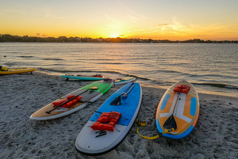 paddleboards on the sand at sunset