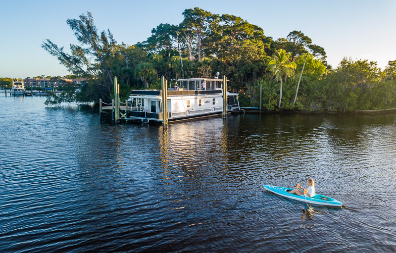 person kayaking past houseboat